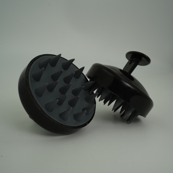 A black Koffeco scalp massager with a round head and flexible bristles, designed for hair care.